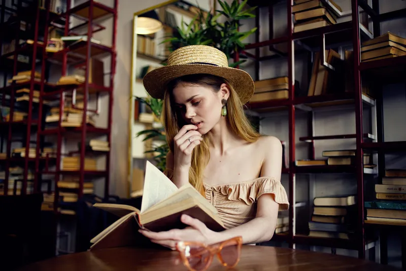Женщина читает книгу, отдыхая в кафе, наслаждаясь напитком