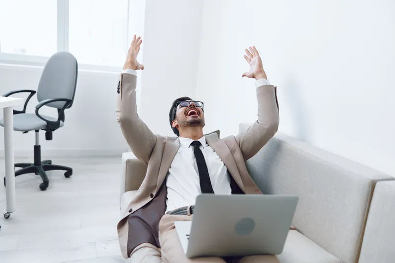 Успешный мужчина работает за ноутбуком в гостиной на диване