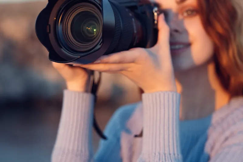 Счастливая женщина-фотограф делает снимок с помощью профессиональной камеры со вспышкой