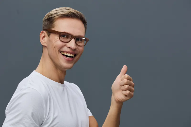happy young caucasian man wear glasses white t-shirt show thumb up gesture smile look camera isolated on grey background casual lifestyle concept