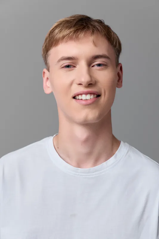 Smiling young man in a white t shirt looking at the camera, soft studio light, neutral background, casual lifestyle vibe, approachable expression suitable for branding, social media and marketing
