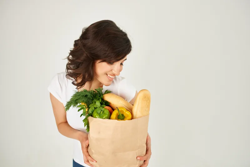 Милая брюнетка с пакетом продуктов, овощами, доставкой здоровой пищи