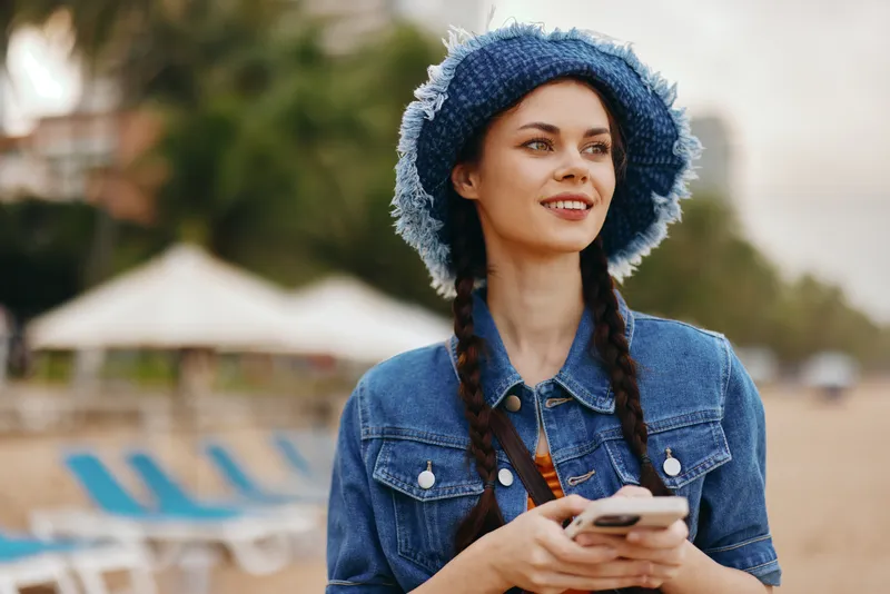 Молодая женщина держит смартфон и наслаждается городским летом с положительными эмоциями