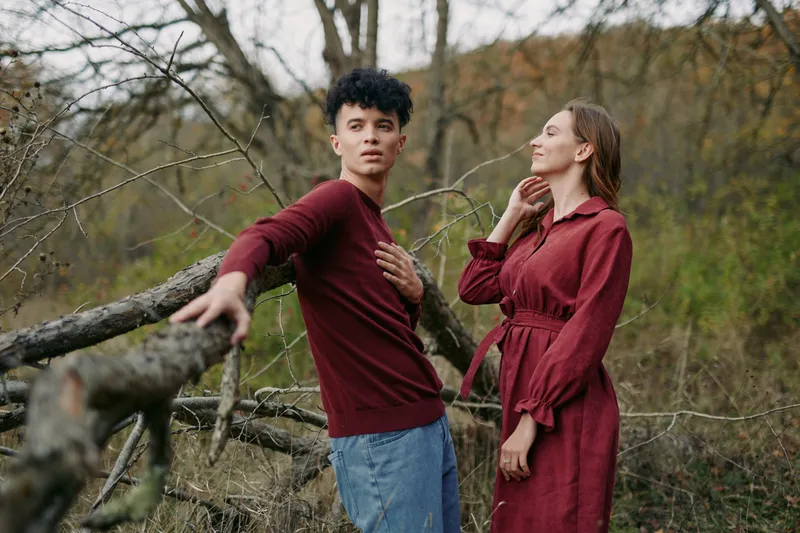 Two individuals stand near a weathered wooden fence, outdoors, presenting a candid scene that radiates authenticity and credibility through natural posture and genuine expression.