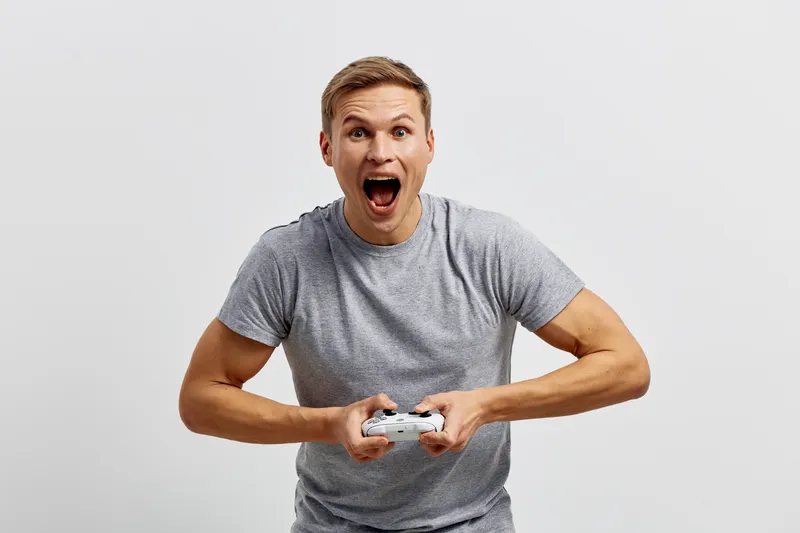 excited young caucasian man play video game hold controller on light background digital detox concept