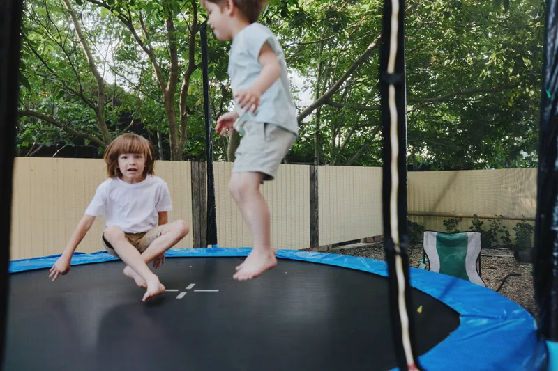 Active boys playing on a trampoline, enjoying the outdoors with laughter and joy. This engaging scene captures the essence of childhood excitement and fun.