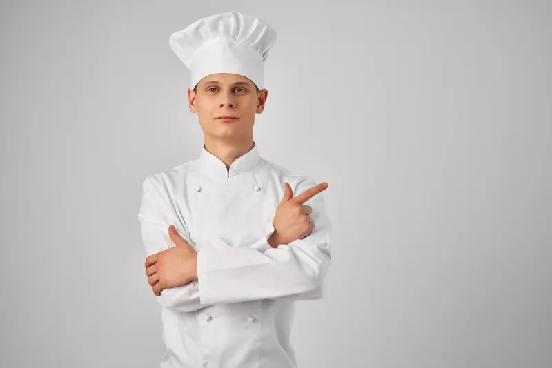 Мужчина в поварской форме жестикулирует рукой, работает в ресторане, профессионал