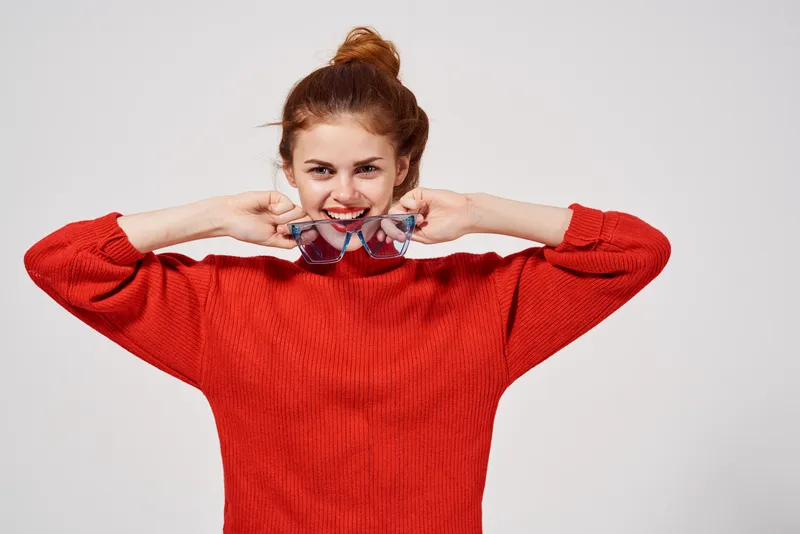 Весёлая женщина с очками в руках, модель, передающая эмоции, в красном свитере