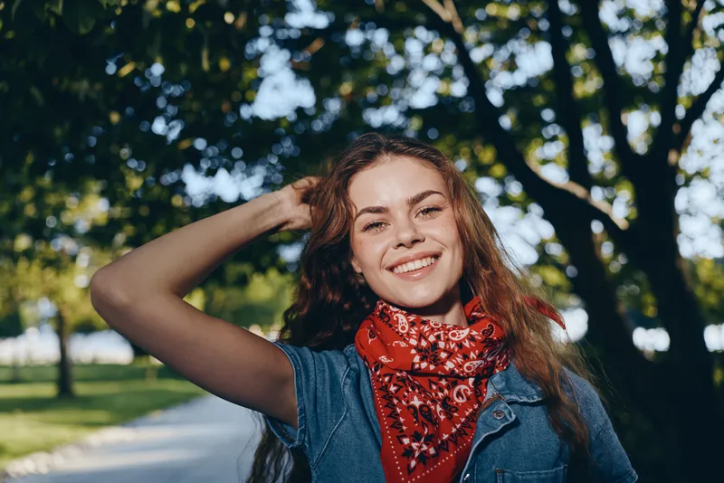 Lifestyle woman in modern boho-western denim street style smiling outdoors with natural sunlight, film color tones enhancing casual youthful vibe and relaxed mood.