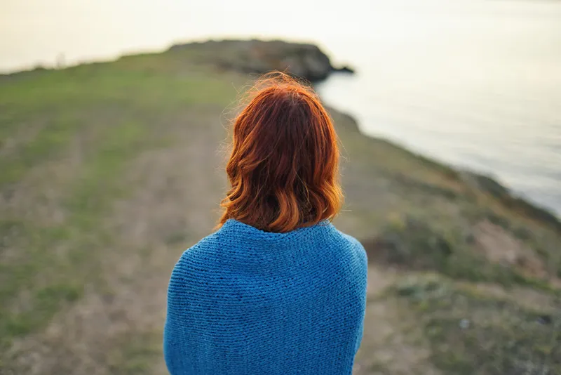 Красивая рыжеволосая женщина любуется природным пейзажем во время путешествия, вид со спины