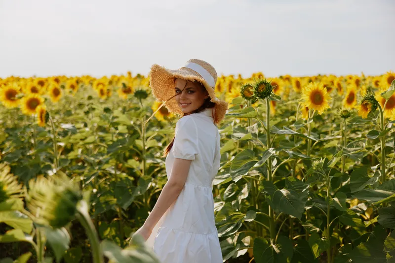 Женщина с двумя косичками в поле с цветущими подсолнухами