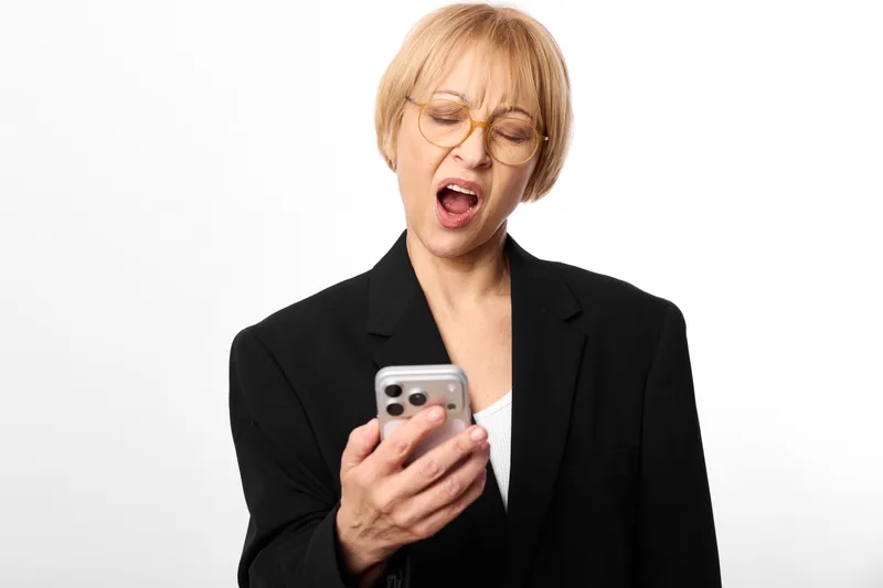 Woman, businesswoman, stress, shouting, phone, smartphone, glasses, anger, panic, workplace, holding a smartphone in black blazer, eyes shut, mouth open, isolated on white background, mental overload