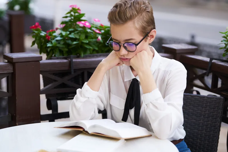 Студент с книгой в руках на открытом воздухе, читает, образование