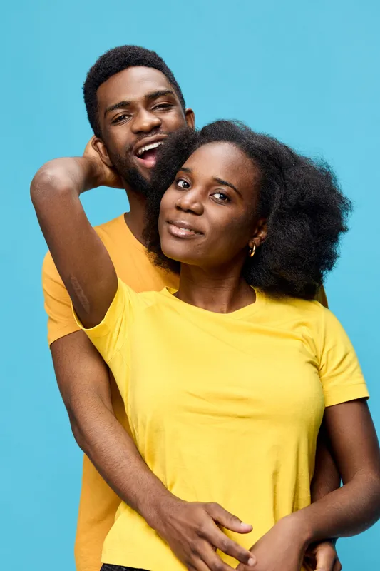 Happy couple in matching vibrant yellow and orange t shirts against a bright blue background, showcasing love and connection