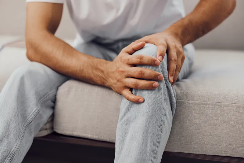 Thoughtful man experiencing AI anxiety during a digital detox, reflecting on work-life blur and mental health struggles in a cozy living space.
