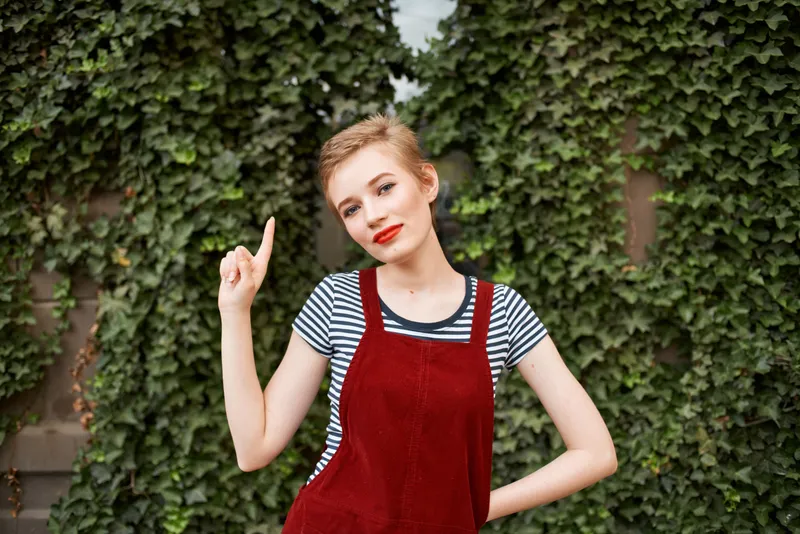 Женщина с красными губами на открытом воздухе на фоне кустарника