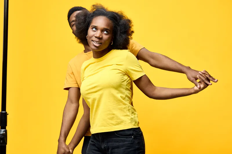 Happy young couple in matching yellow shirts on a vibrant yellow background, showcasing joy and connection Perfect for themes of love and friendship