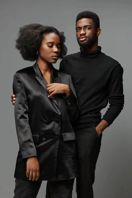 Elegant black couple in stylish outfits, capturing modern fashion expression with confident emotions and neutral background, perfect for lifestyle imagery