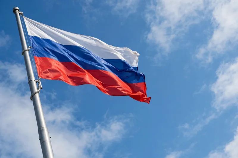 Российский флаг развевается на фоне голубого неба с облаками