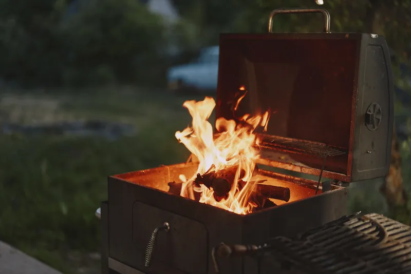 Warm glow of flames in a barbecue grill, creating a cozy outdoor atmosphere, perfect for summer gatherings and delicious grilled meals