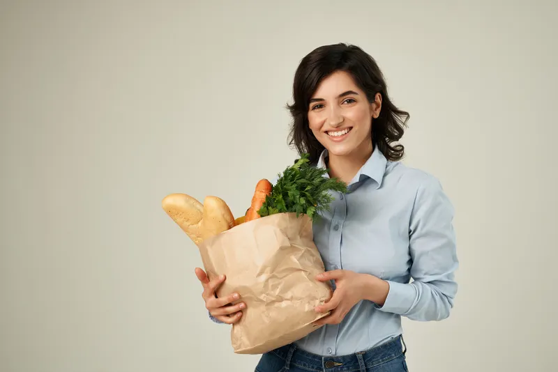 Женщина в синей рубашке упаковывает продукты в супермаркете