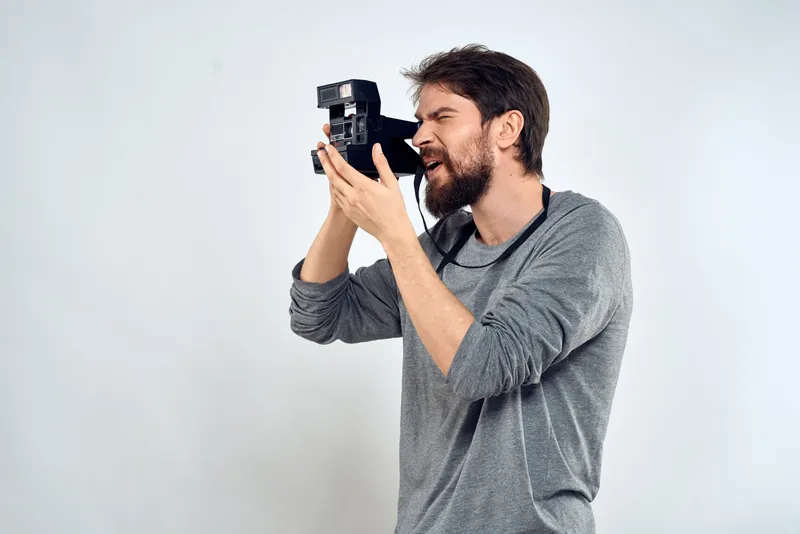 Мужчина-фотограф с профессиональной камерой работает в студии