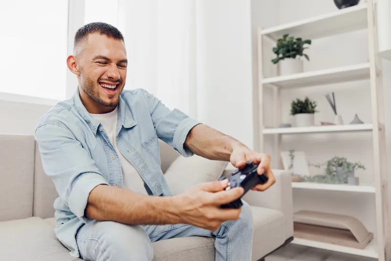 Engaged man playing video games at home, showcasing the balance between leisure and technology, reflecting modern challenges and self-care.