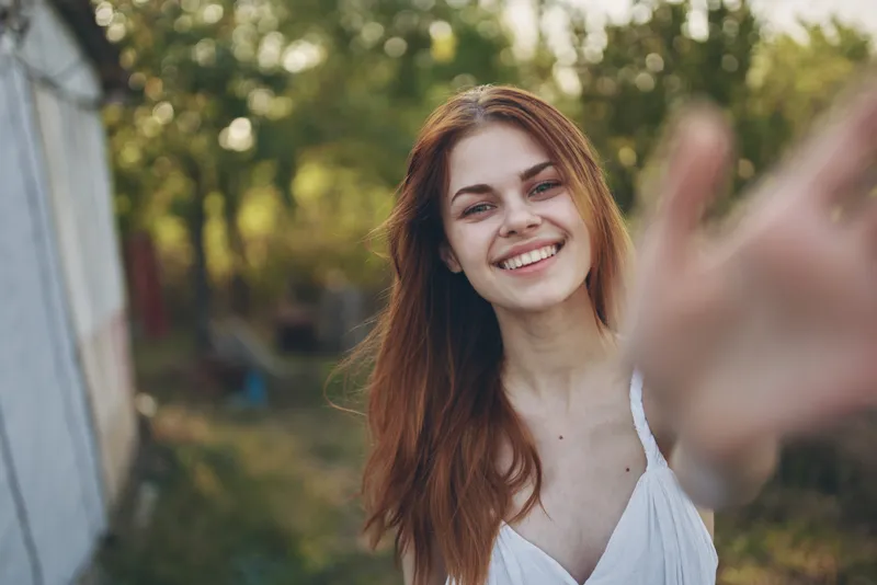 Счастливая женщина жестикулирует руками на открытом воздухе в саду, лето, деревья, отдых