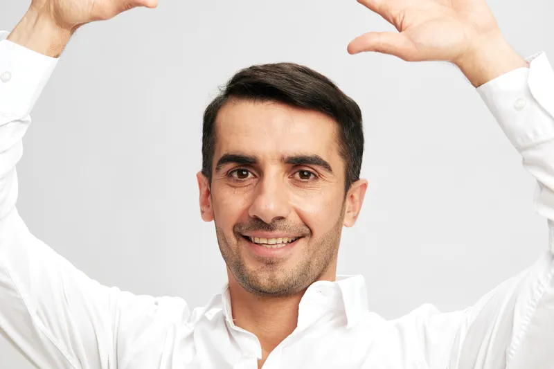Менеджер в белой рубашке держит руки над головой, уверенность в себе на изолированном фоне