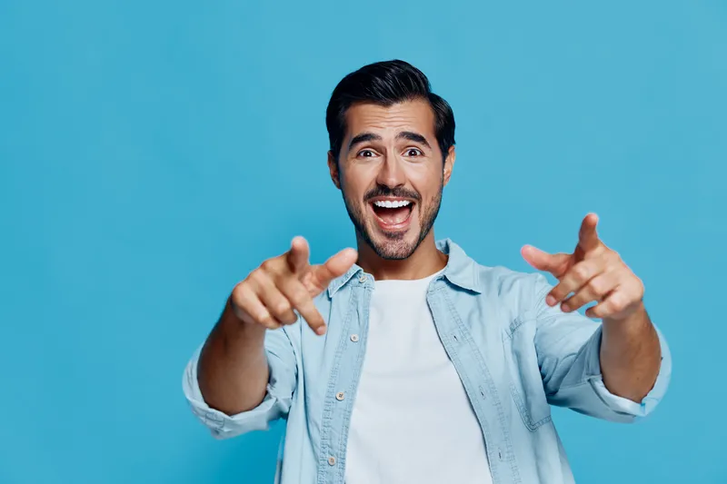 Full body smiling cheerful young man wear casual shirt look at camera point fingers isolated on bright bold blue background studio portrait. People joy concept.
