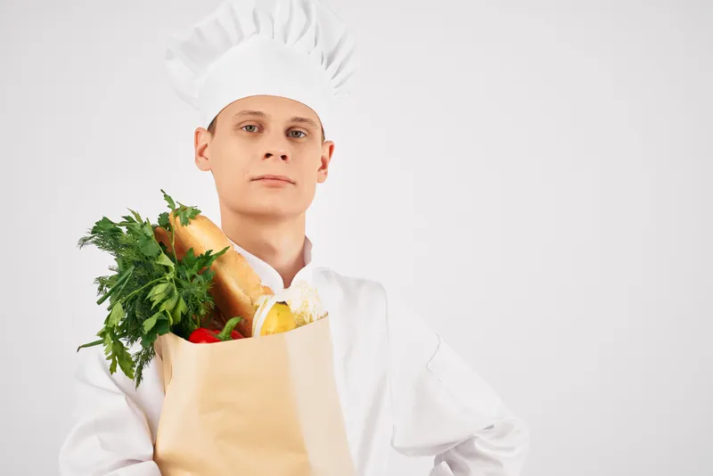 Мужчина в форме повара занимается доставкой продуктов из супермаркета