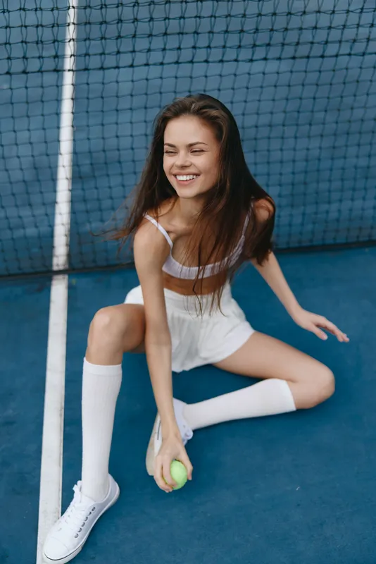 Young female athlete enjoying tennis on a court, showcasing sportswear, vibrant emotions, and an energetic atmosphere for fitness enthusiasts