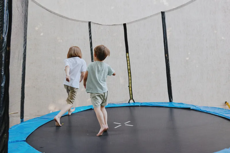 Playful children enjoying time on a trampoline, engaging in fun activities, and sharing laughter under a bright sky.