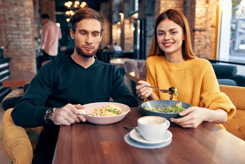Мужчина и женщина сидят за столом в ресторане, наслаждаясь вкусной едой и подачей блюд