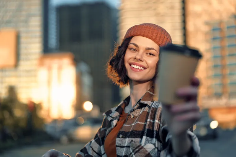 Woman coffee smile urban portrait candid moment of a young female holding takeaway cup in warm city light, authenticity and candid lifestyle with golden hour glow, mindful living, emotional