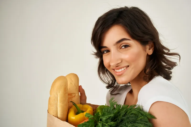 Женщина в белой футболке с пакетом продуктов, крупный план в супермаркете