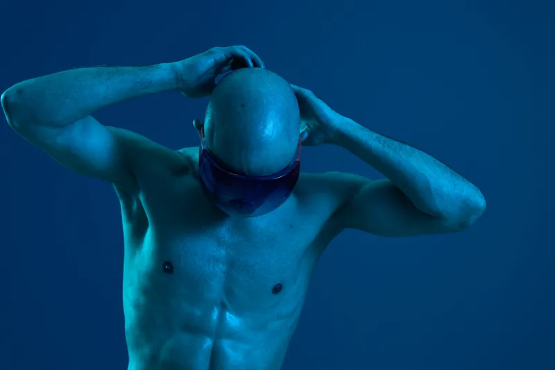 Athletic man in a blue light, showcasing strength and determination, emphasizes an energetic and futuristic vibe in a unique setting.