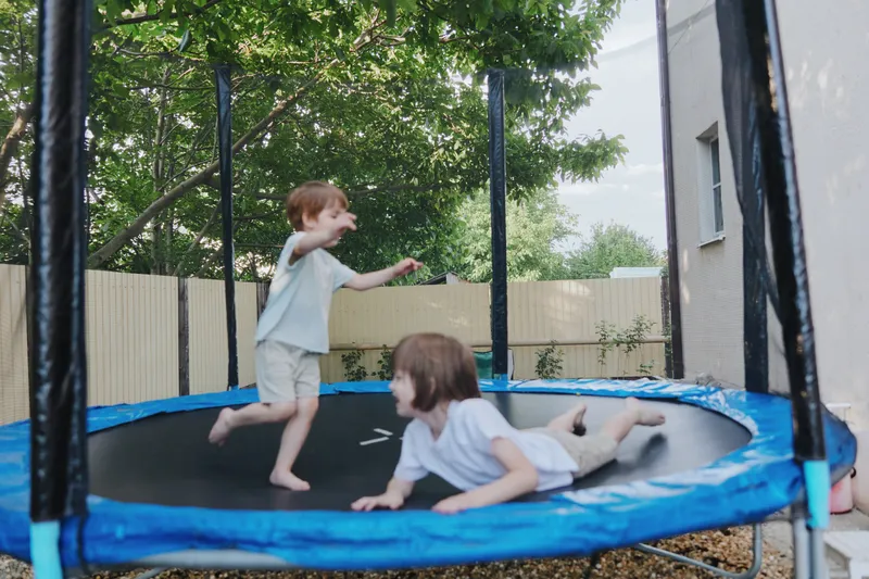 Active children enjoying a trampoline in a sunny backyard, creating joyful moments full of laughter and playfulness during a warm summer day.