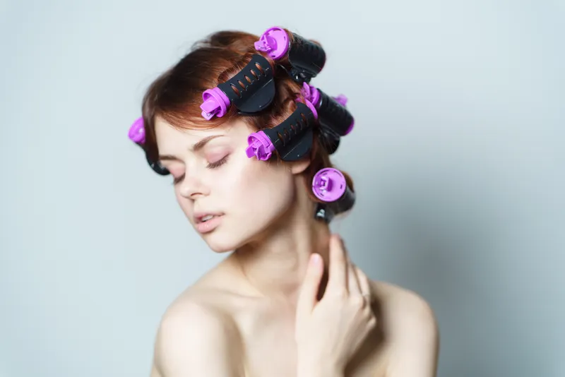 Симпатичная женщина с бигуди на голове, прическа, обнаженные плечи, макияж