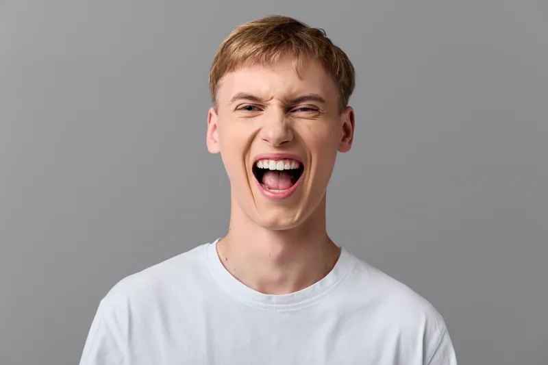 Shouting man with wide open mouth expressing excitement and energy, raw emotion captured in studio, dynamic facial expression, strong vocal gesture and lively mood for advertising use