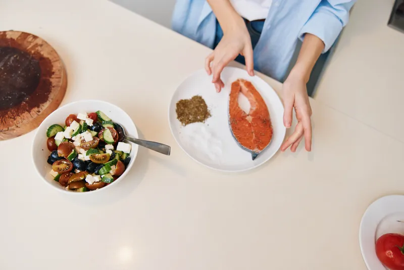 Женщина готовит свежее и полезное блюдо из овощей и мяса на кухонной стойке