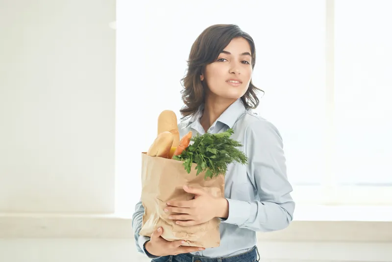 Женщина с пакетом продуктов на кухне