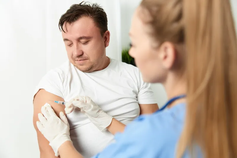 Врач делает инъекцию в руку мужчины, вакцинация для здоровья