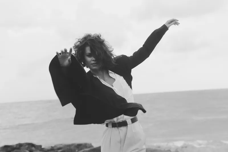 Dance, dancer, movement, beach a windblown figure in a flowing coat on a windy shore capturing freedom and expression in a monochrome seascape with a dynamic pose