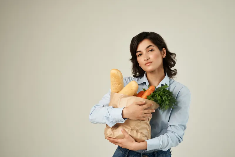 Брюнетка с пакетом продуктов в супермаркете: здоровая еда, овощи, образ жизни