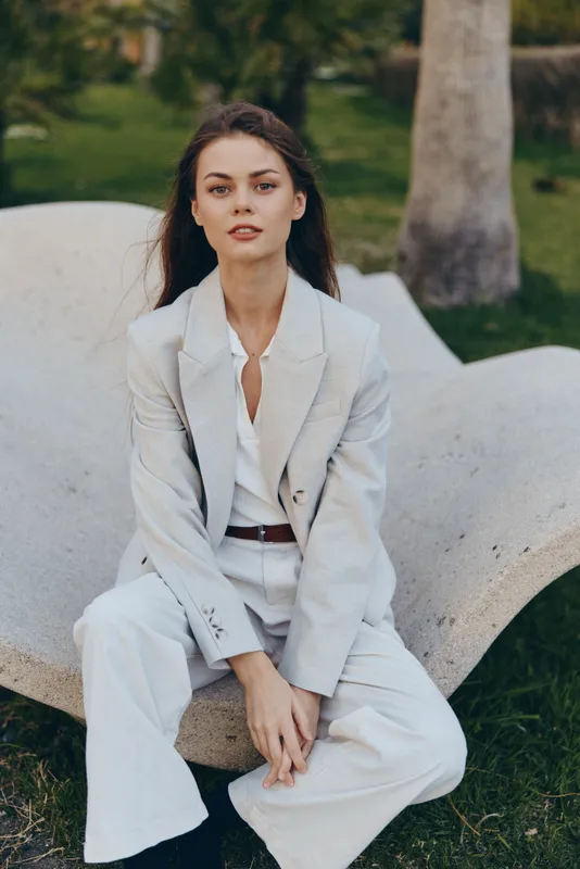 Professional woman in stylish business attire sits confidently outdoors, showcasing a modern and fresh approach to workwear in a natural setting.