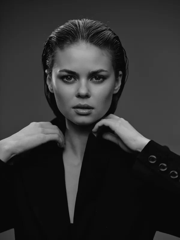 black and white portrait of serious woman with wet hair in dark jacket looking at camera