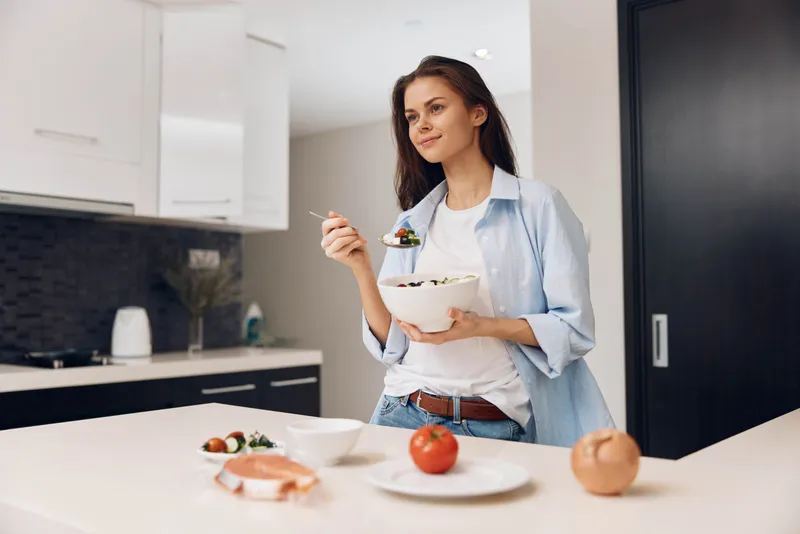 Женщина стоит на кухне с миской еды перед собой, готовя вкусное домашнее блюдо