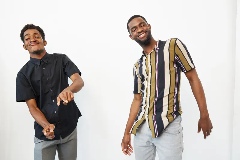 Two cheerful African American men dancing together, showcasing friendship and joy in a bright, stylish setting full of vibrant colors and positive energy.