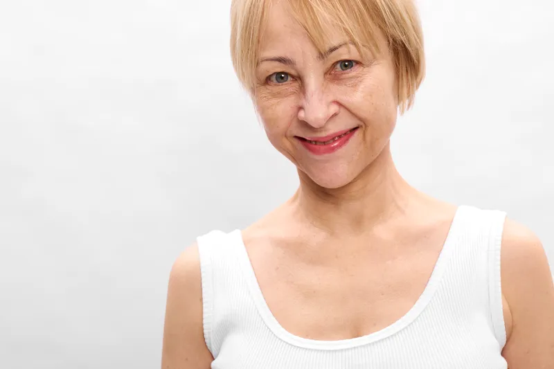 Woman portrait skincare selfcare wellness cream, white studio close up, short blonde hair woman in white top, soft light, calm smile, beauty routine, skin hydration, gentle care